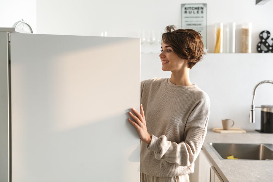 Woman searching an open fridge