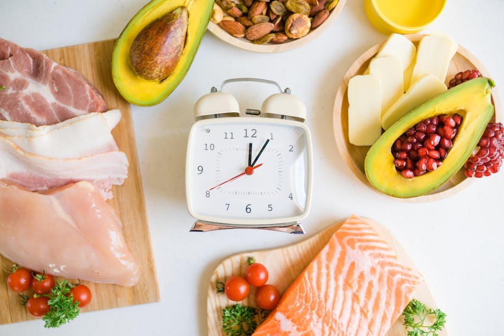 Blue alarm clock on a table with low-carb foods