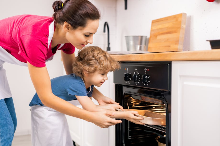 Mom and son placing food in the oven