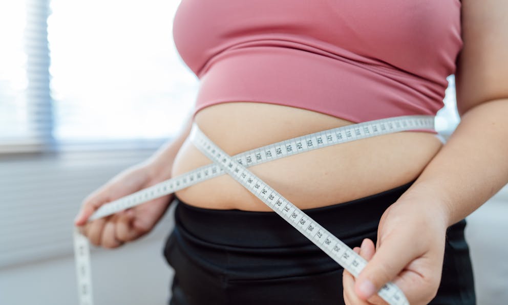 Overweight woman measuring her waist