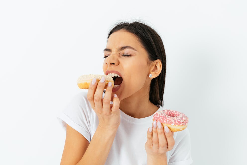 hungry young woman craving eating donuts