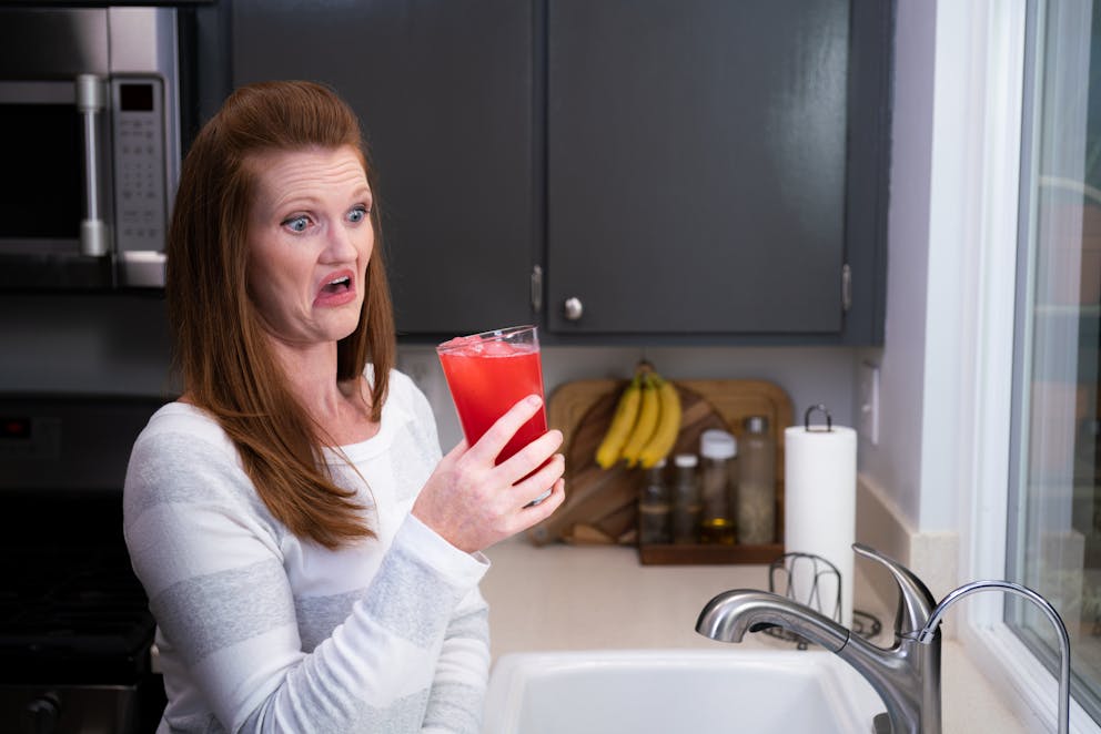 Woman disgusted by red drink