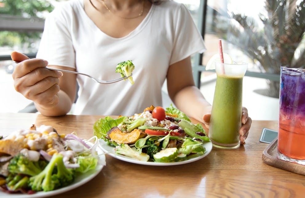 Woman eating large salad and smoothie