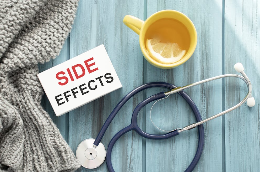"Side effects" text on card with tea mug and stethoscope on wooden table.