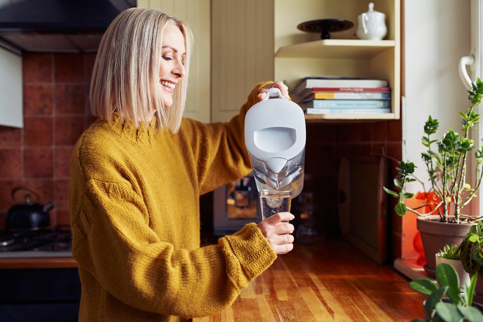 Woman using a water filter jug