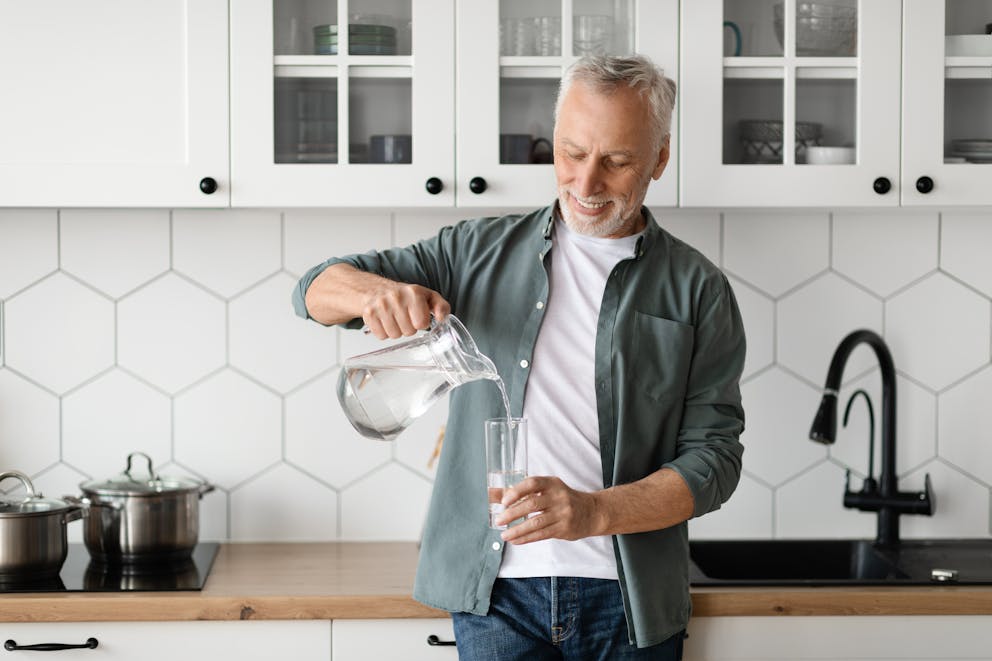 Senior man pouring water into a glass