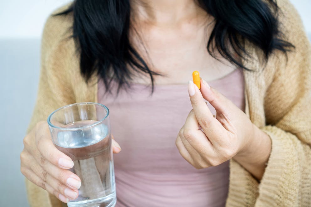 Woman holding a turmeric pill in her hand