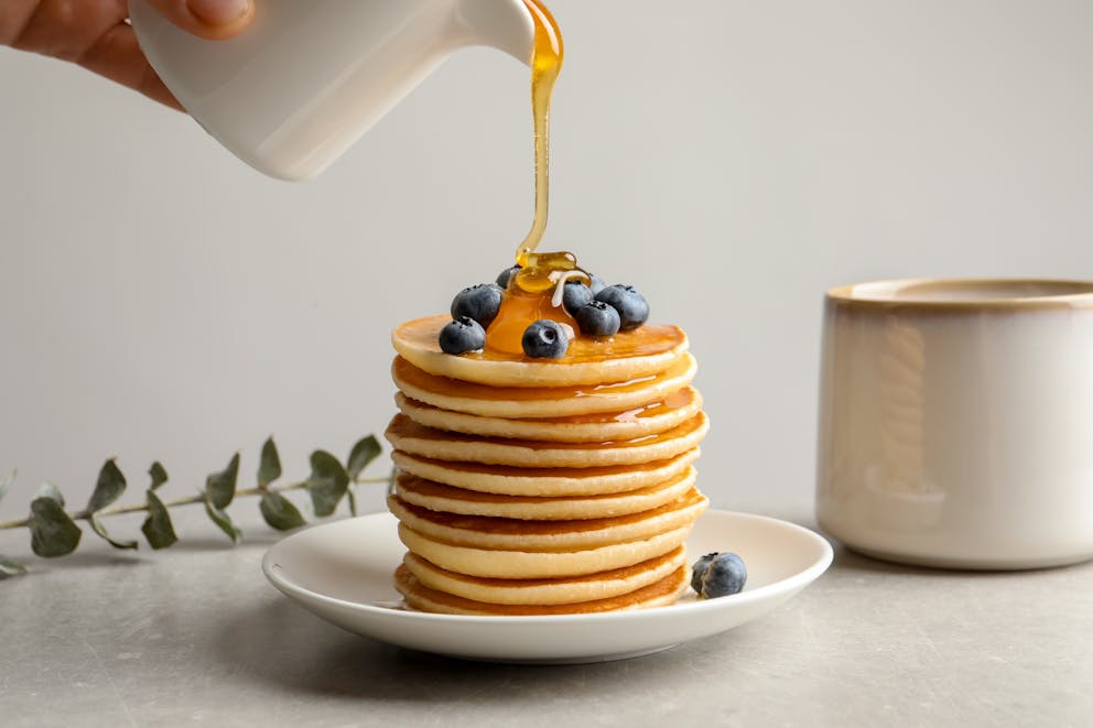 Pouring honey on pancakes