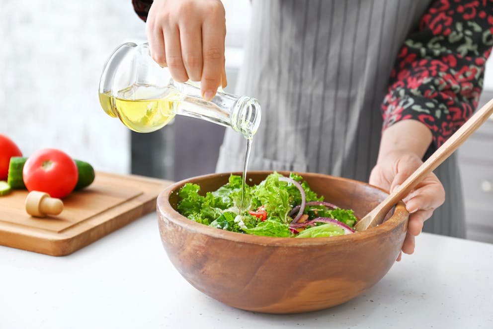 Pouring olive oil over salad