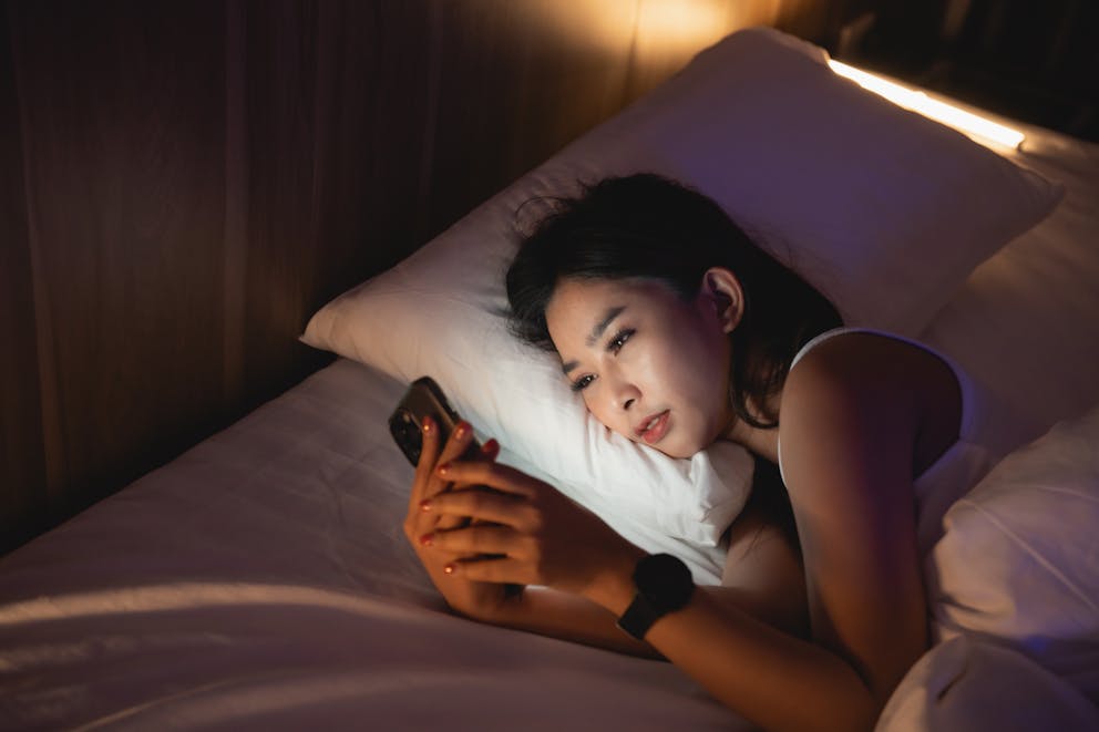 Women in bed using phone