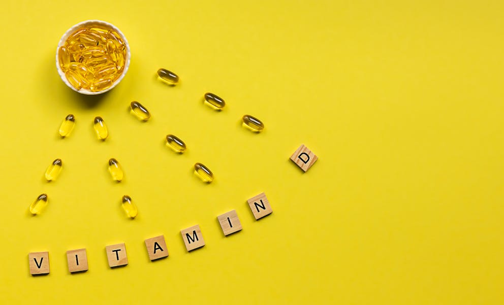 Vitamin D capsules on yellow background
