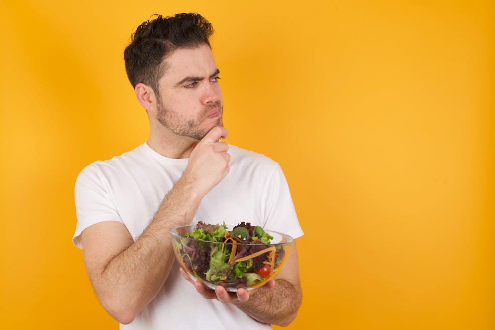 Young man thinking about salad