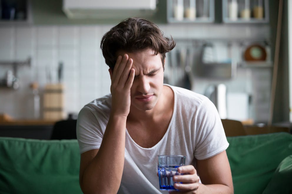 Man with headaches holding a glass of water