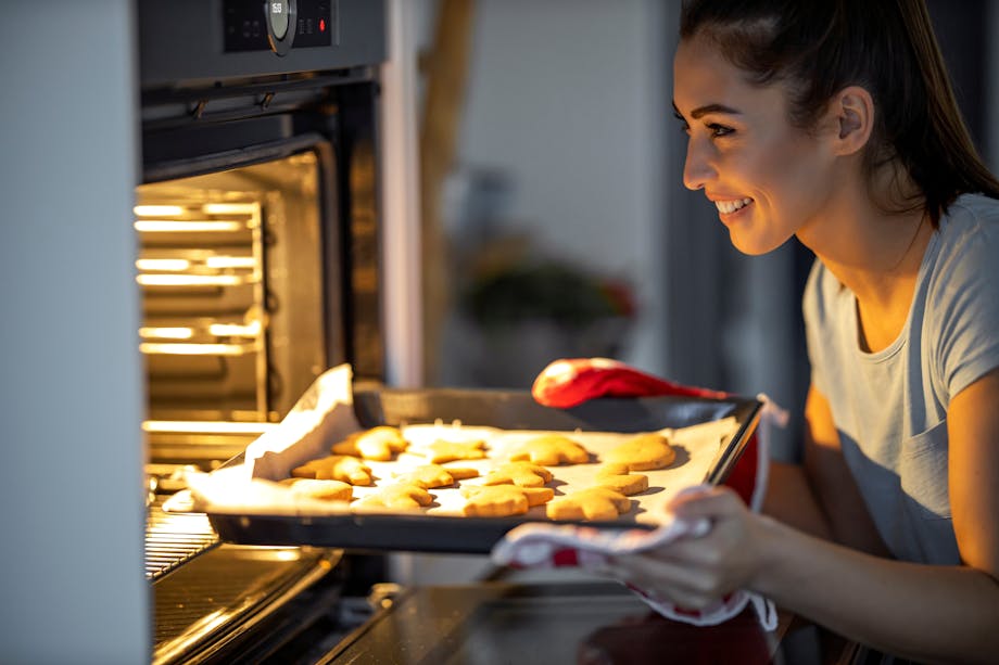 Woman taking out cookies from oven