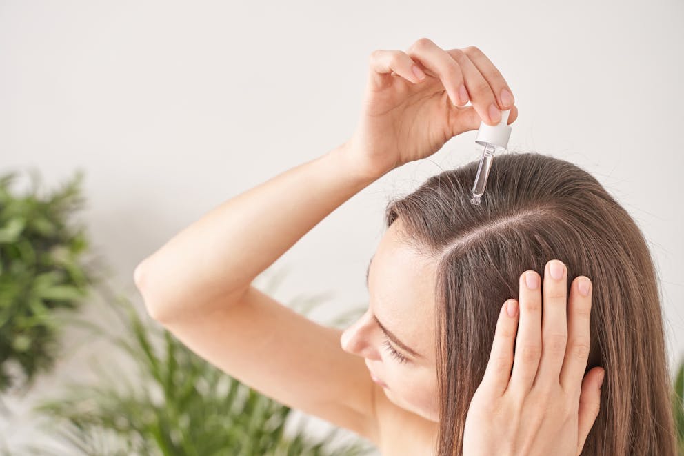 Woman applying castor oil to hair