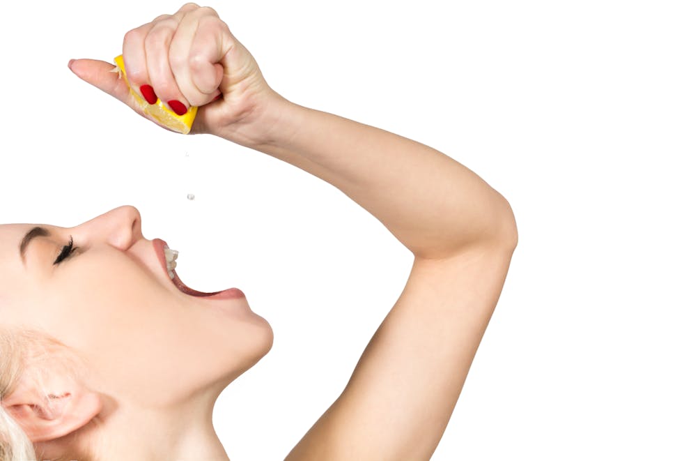 Woman squeezing lemon juice into her mouth